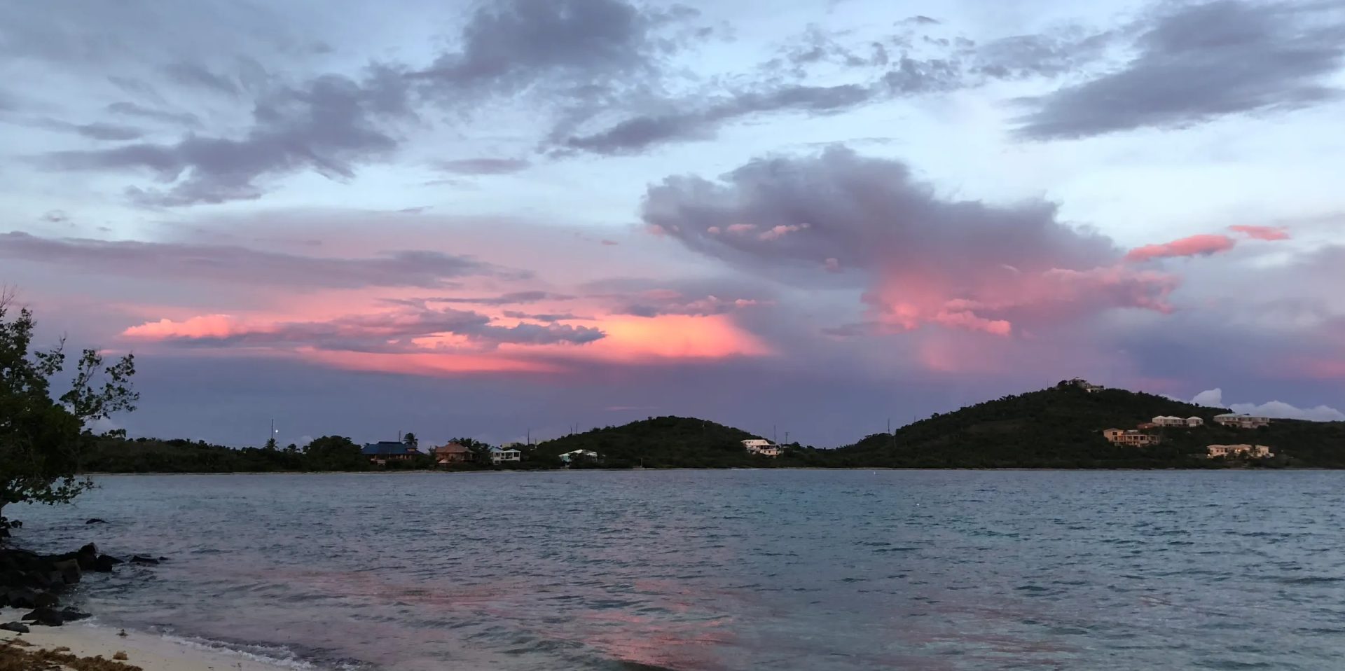Sunset clouds over a calm lake and forested hills